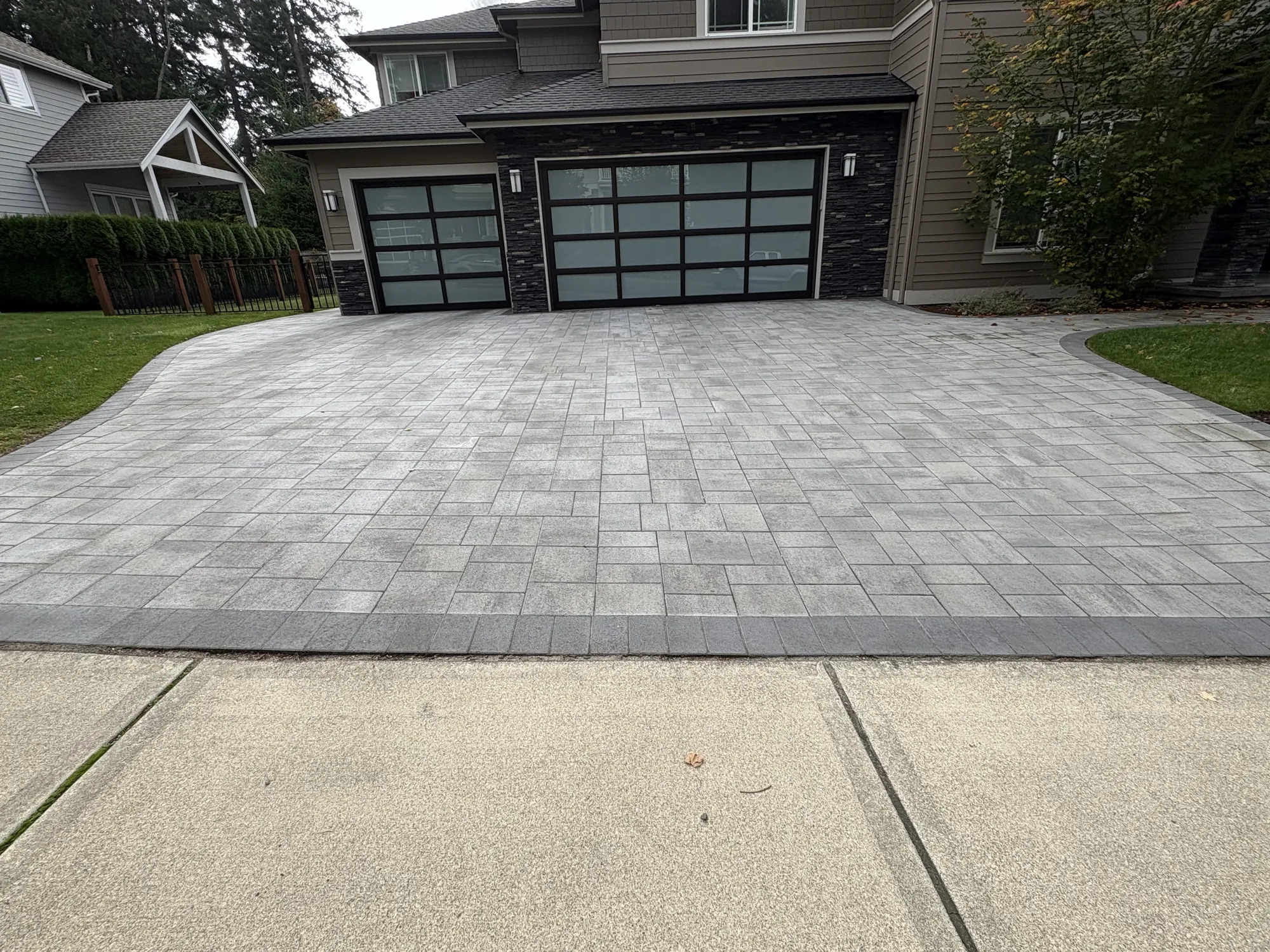 Gray paver driveway leading to a home's garage