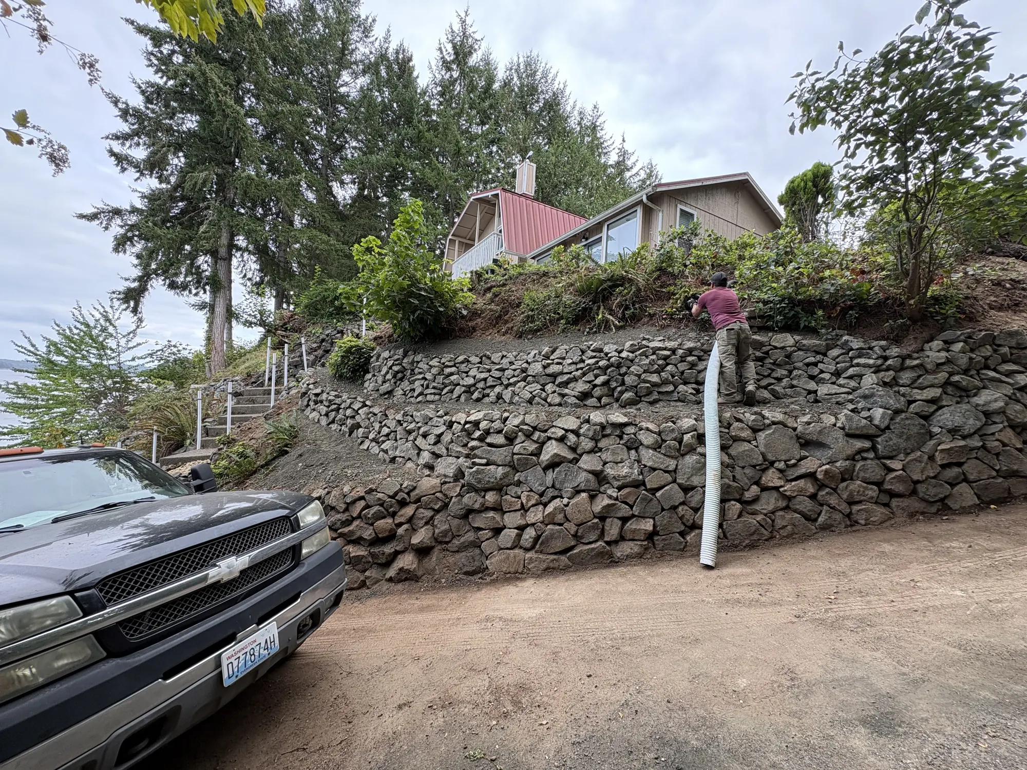 Stone retaining wall and hillside planting beside a home